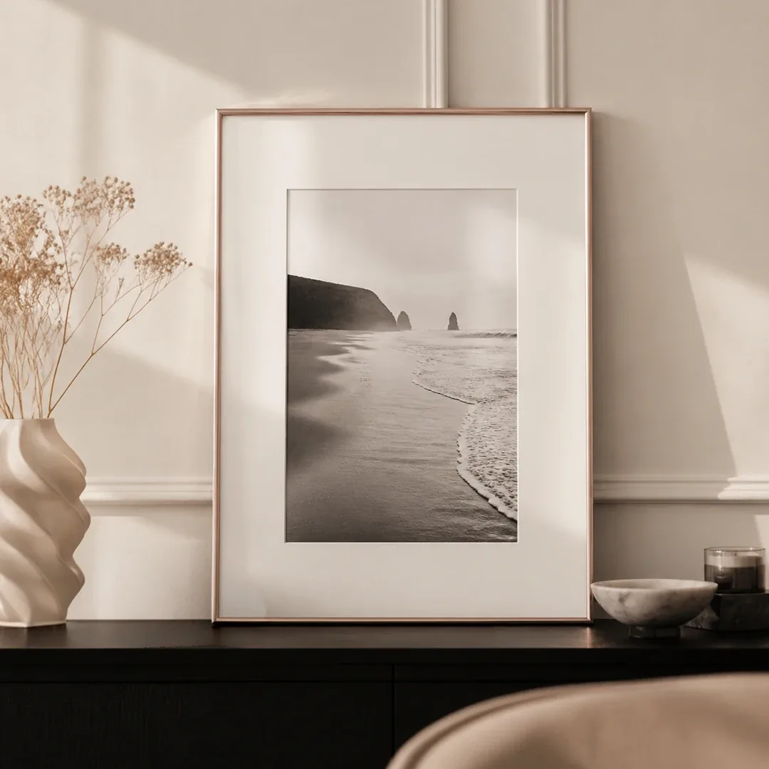 Weißer Kunststoffrahmen mit Schwarz-Weiß-Strandfoto und Passepartout auf einer Kommode