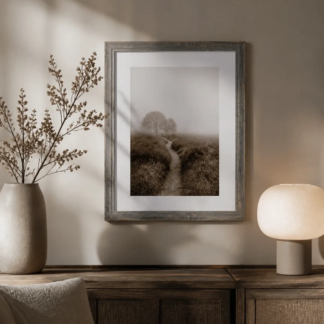 Grau gewischter Vintage-Rahmen mit Landschaftsfoto an der Wand über einer Holzkommode
