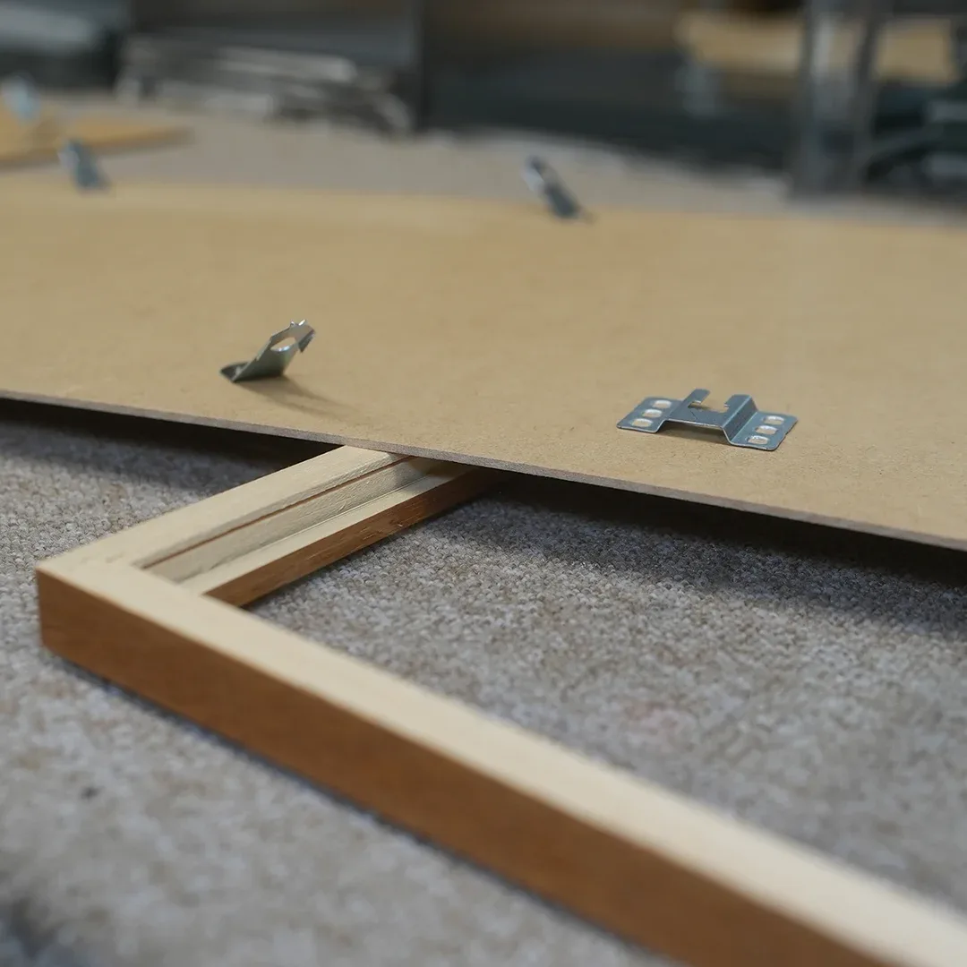 Rückwand mit Drehhaltern und Aufhänger über einem hellen Holzrahmen auf der Werkbank